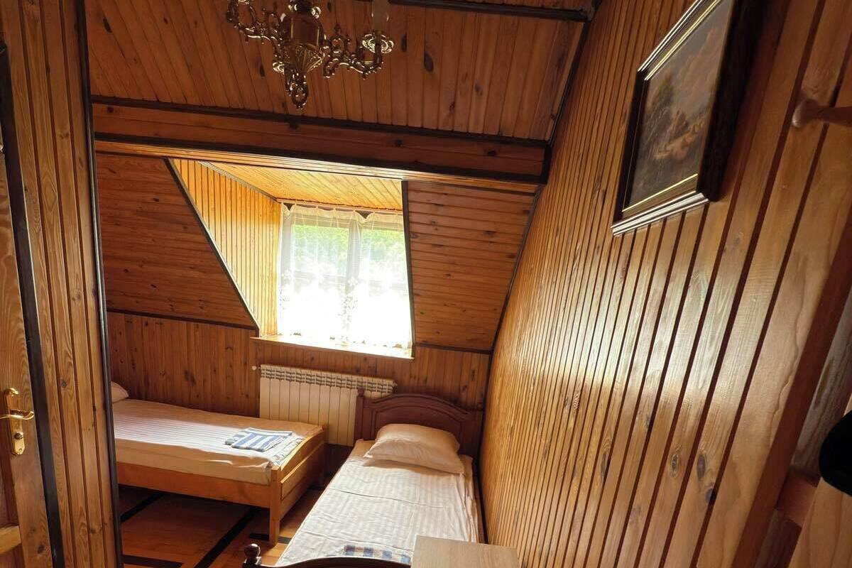 A small, wooden cabin room with a bed, a desk, and a chair.