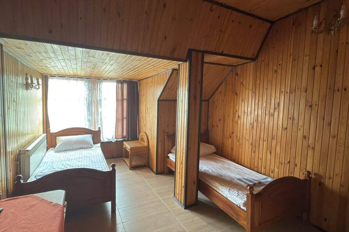 A wooden cabin with two single beds, a small table, and a bench.
