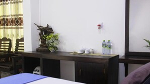 A hotel room with a bed, a desk with a potted plant, a water dispenser, and a chair. - Punsisi Resort - Delhousie Adamspeak (Nallathanniya)