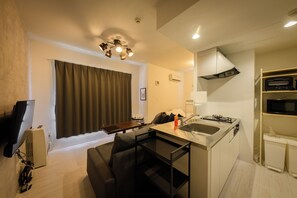 A compact living space with a kitchenette, a dining area, and a seating area. - EFFECT Kikusui (Sapporo)