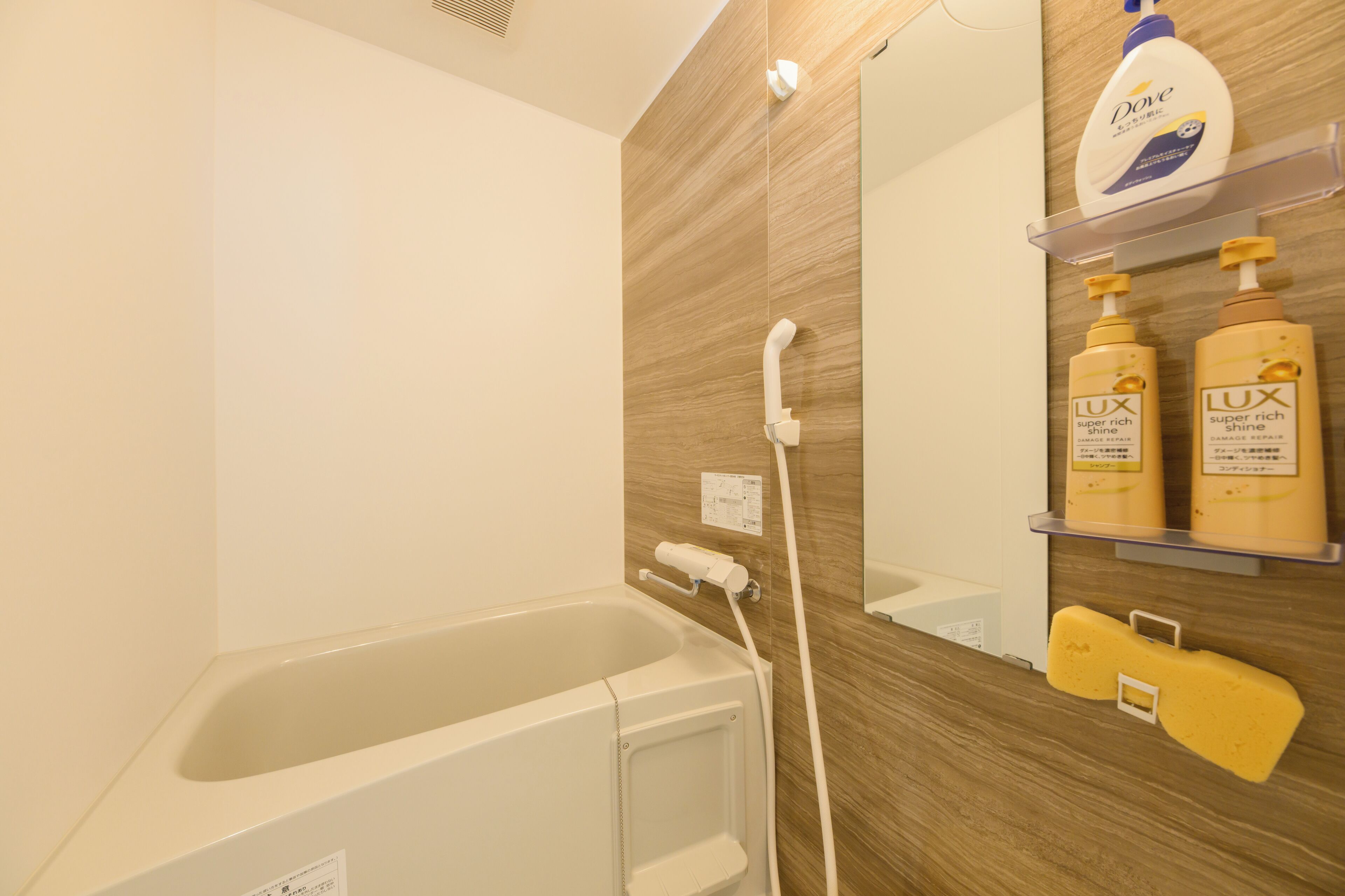 Een badkamer met een badkuip, een handdouche en toiletartikelen op een plank.