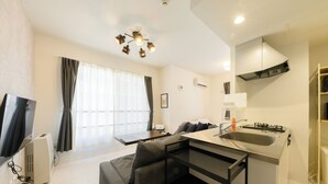 A compact living space with a kitchenette, a sofa, a dining table, and a TV. - EFFECT Kikusui (Sapporo)