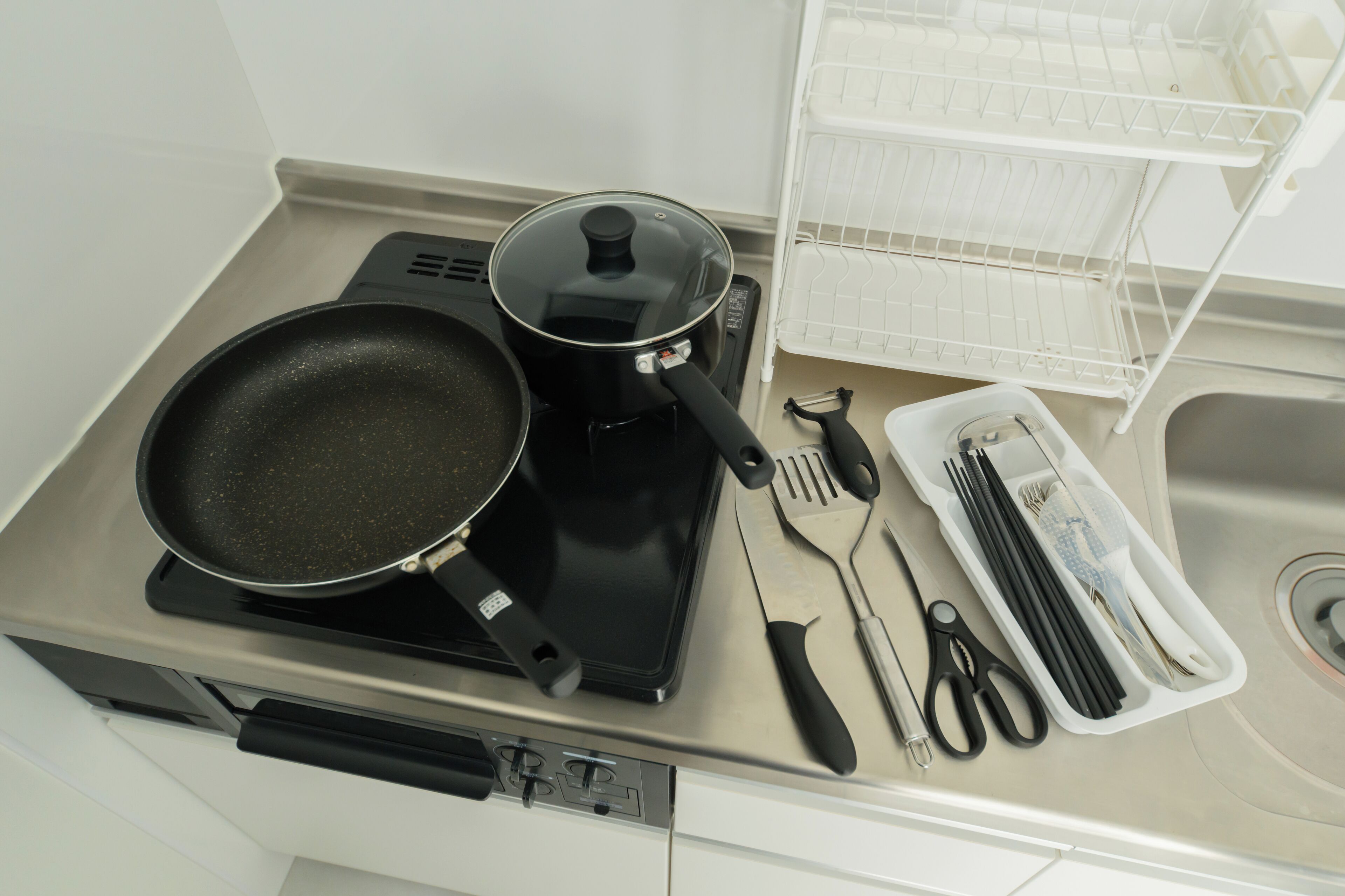 A kitchen with a stove, a frying pan, a pot, and a utensil holder.