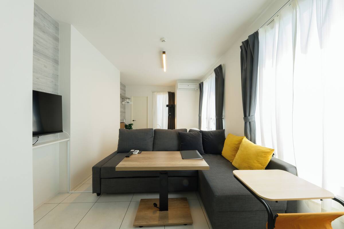 Una sala de estar moderna con un sofá modular, una mesita y un televisor montado en la pared.