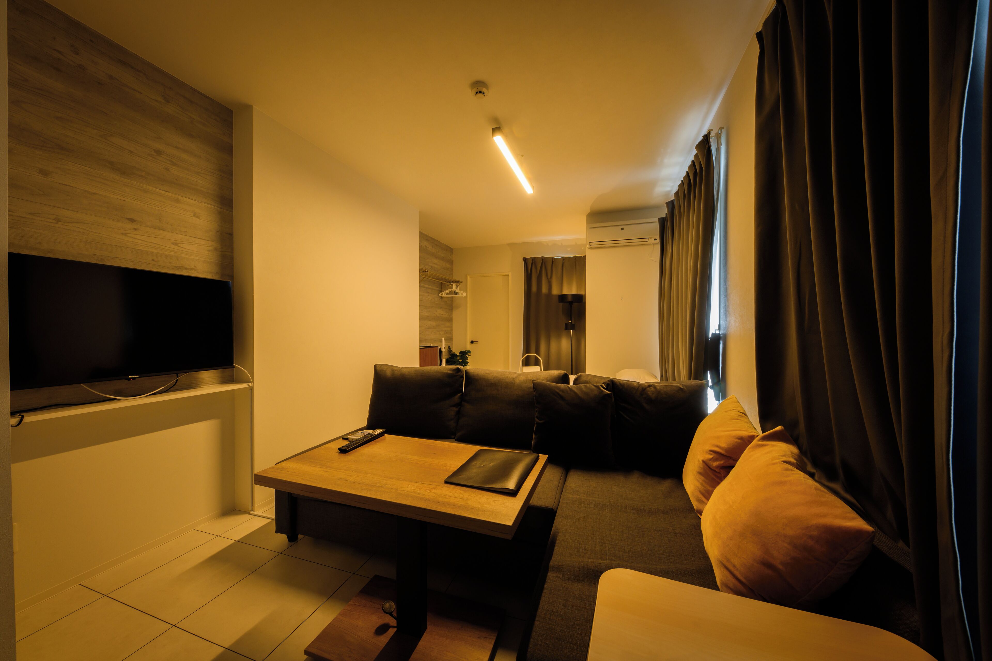 A modern living room with a flat-screen TV, a wooden coffee table, and a sofa with cushions.