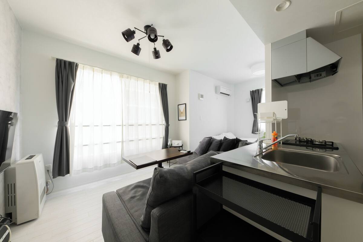 Una sala de estar moderna con un sofá, una mesa de comedor y una zona de cocina con fregadero y estufa.