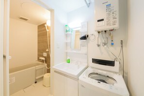 A modern bathroom with a bathtub, a sink, and a washing machine. - EFFECT Kikusui (Sapporo)