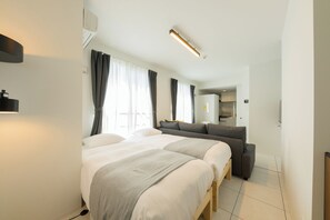 A modern hotel room with a large bed, a sofa, and a kitchenette. - EFFECT Kikusui (Sapporo)