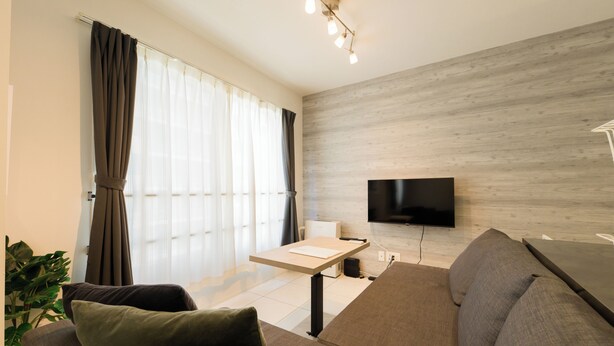 A modern living room with a flat-screen TV, a sofa, a coffee table, and a potted plant. - EFFECT Kikusui (Sapporo)