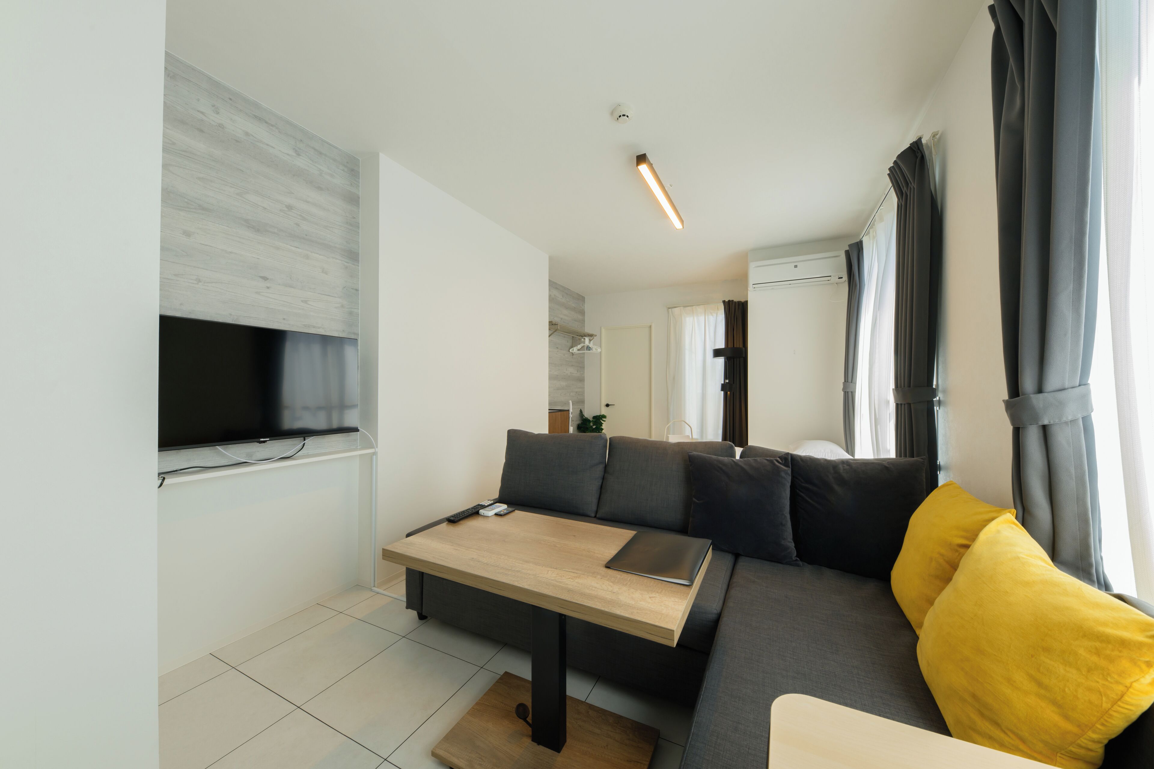 A modern living room with a sofa, a coffee table, and a flat-screen TV mounted on the wall.