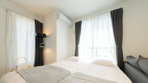 A hotel room with a large bed, a bedside table, an air conditioning unit, and a sofa. - EFFECT Kikusui (Sapporo)