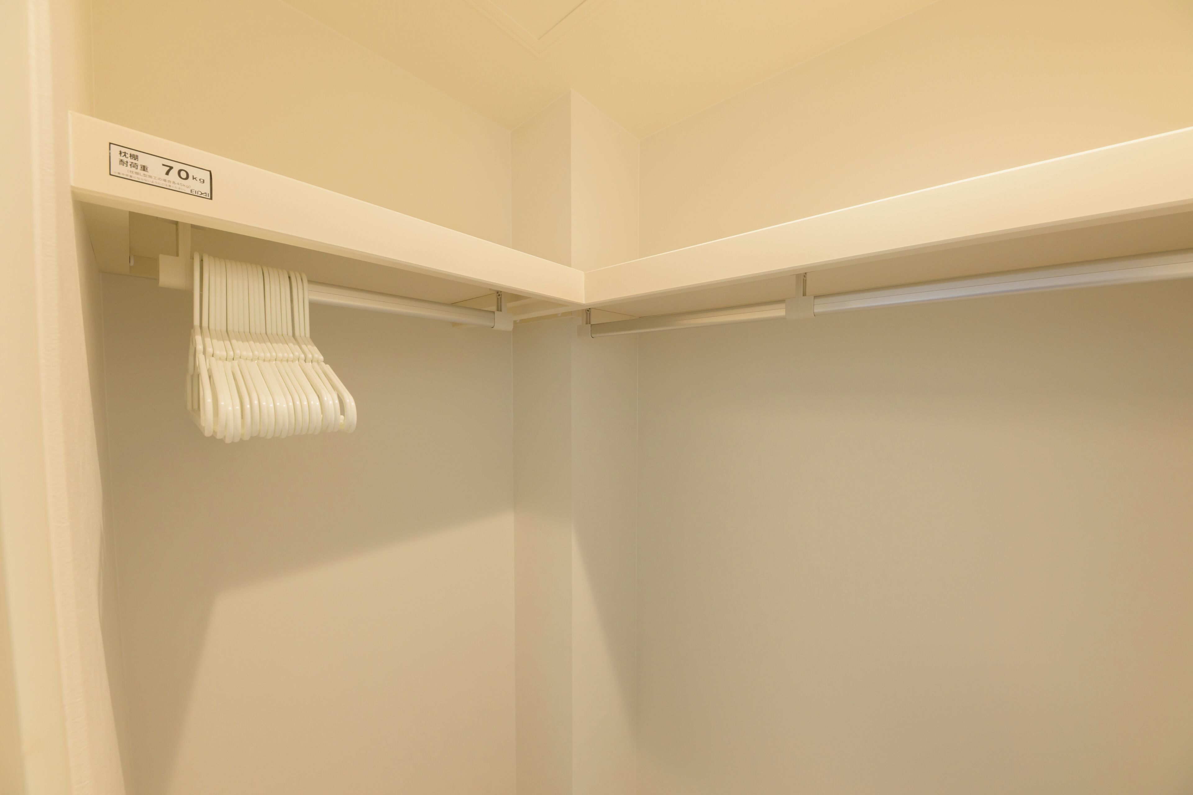 A corner of a room with a white closet and a hanging towel rack.