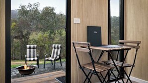 A room with a large window, a small table, two chairs, and a fireplace. - Churinga Orchards by Tiny Away (Lenswood)