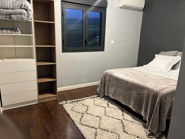 A bedroom with a bed, a wardrobe, a window with a view, and a carpet.