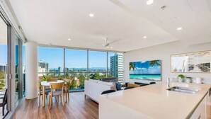 A modern apartment with a large balcony, a dining area, a living room, and a kitchen with a view of the city.