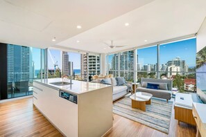Ein modernes Wohnzimmer mit einer großzügigen Kücheninsel, großen Fenstern mit Blick auf die Stadt und einem minimalistischen Design.