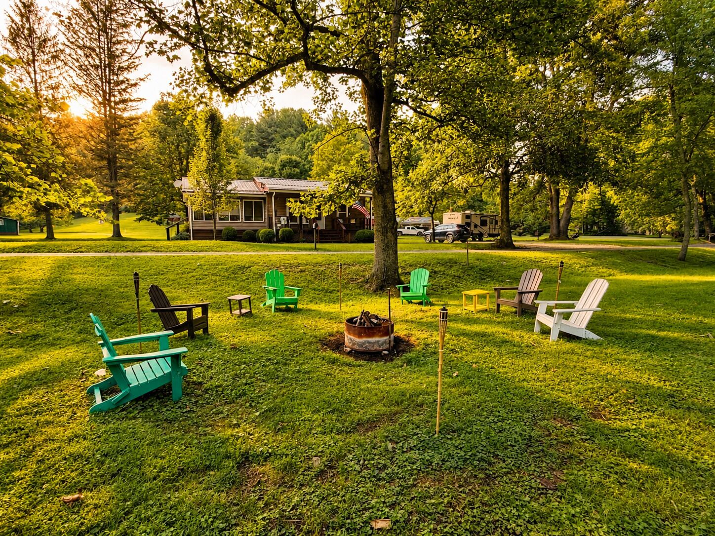 Un espacio al aire libre con césped, sillas Adirondack, un hoyo para la hoguera y una casa al fondo.