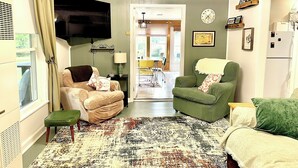 A living room with a sofa, a chair, a table, a lamp, a TV, and a patterned rug.