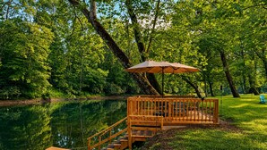 A wooden dock extending into a lake, surrounded by lush greenery.
