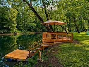A wooden dock extending into a lake, surrounded by lush greenery.