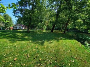 A grassy area with trees and a house in the background.