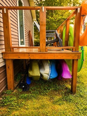 A wooden deck with a bench, a bicycle, and various colorful children's toys underneath.