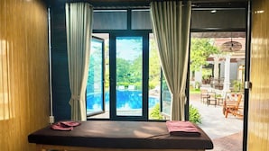 Ein Massagetisch mit Blick auf ein Pool- und Terrassenbecken.