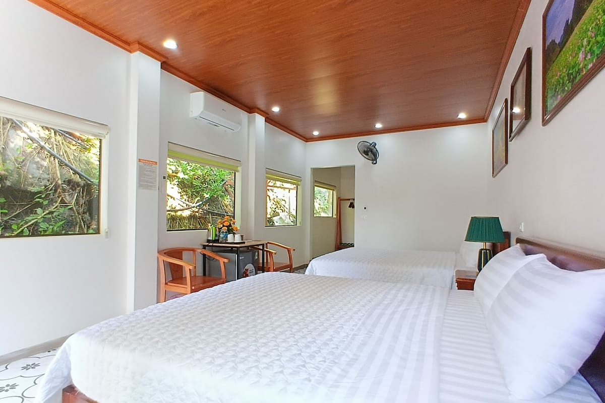A bedroom with a large bed, wooden ceiling, and a small table with chairs.