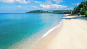 A beach with clear turquoise water, a sandy shore, and a forested hill in the background. - Bellevue Lagoon Premium Apart Hotel (Choeng Thale)