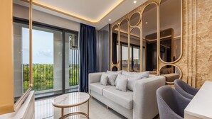 A modern living room with a sofa, a round coffee table, and a large mirror. - Bellevue Lagoon Premium Apart Hotel (Choeng Thale)