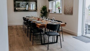 A dining area with a long wooden table set for six, surrounded by black chairs. - Modern Country Escape for 12 Guests -Rural Setting (Llanarthney)