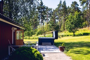 A cabin with a deck, a hot tub, and a view of a forested area. - Stay North - Pohjola (Naantali)