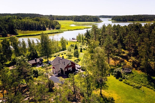 A large house with a spacious yard, a small pond, and a forested area.