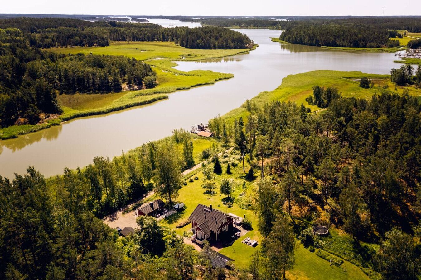 A large house surrounded by a forest and a lake.