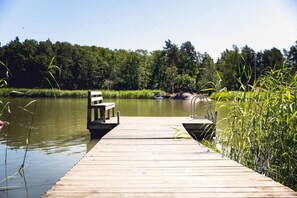 A wooden dock extending into a calm lake, with a bench and a small boat docked at the end.