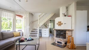 Een moderne woonkamer met een bank, salontafel, open haard en een trap die naar een keuken leidt.