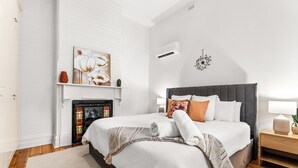 Un dormitorio con cama, chimenea y aire acondicionado instalado en la pared.