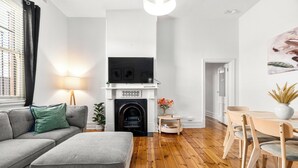 Una sala de estar moderna con chimenea, un sofá, una mesa de comedor con sillas y un televisor montado sobre la chimenea.