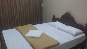 A single bed with a wooden headboard, white linens, and a brown blanket. - AER Residency (Tiruvannamalai)