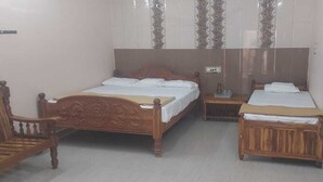 A bedroom with two wooden beds, a nightstand, a chair, and a wardrobe. - AER Residency (Tiruvannamalai)