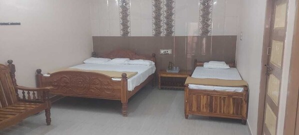 A bedroom with two wooden beds, a nightstand, a chair, and a wardrobe. - AER Residency (Tiruvannamalai)