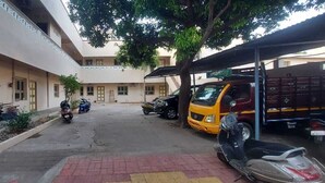 A courtyard with multiple motorcycles and a yellow truck parked under a covered area. - AER Residency (Tiruvannamalai)