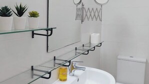 A modern bathroom with a white sink, toilet, and glass shelves. - 1st Class Pool View Apt. (Paphos)