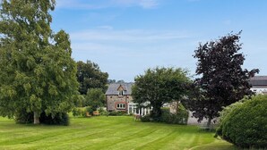A well-maintained lawn with a stone building in the background. - Henfaes Bach - UK50268 (Nannerch, near Clwydian Range)