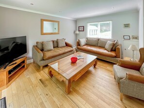A living room with a TV, two sofas, a coffee table, and a window. - 3 bedroom accommodation in Kenmore, near Pitlochry (Kenmore, near Pitlochry)