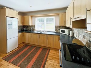 A modern kitchen with wooden cabinets, a black countertop, a stainless steel stove, and a window with blinds. - 3 bedroom accommodation in Kenmore, near Pitlochry (Kenmore, near Pitlochry)