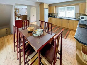 A modern kitchen with wooden cabinets, a dining area with a wooden table and chairs, and a view of the outside through a window. - 3 bedroom accommodation in Kenmore, near Pitlochry (Kenmore, near Pitlochry)