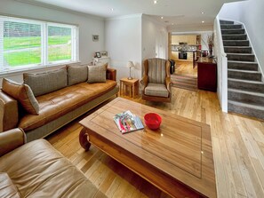 A modern living room with a leather sofa, a wooden coffee table, and a chair. There is a staircase leading to an upper level. - 3 bedroom accommodation in Kenmore, near Pitlochry (Kenmore, near Pitlochry)