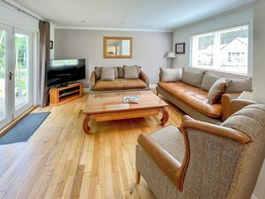 A living room with a wooden coffee table, two sofas, a TV, and a large window. - 3 bedroom accommodation in Kenmore, near Pitlochry (Kenmore, near Pitlochry)