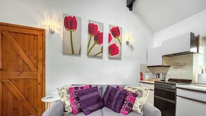 A living room with a grey sofa, a small white table, and a kitchen in the background. - Henfaes Bwthyn - UK50266 (Nannerch, near Clwydian Range)